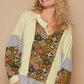 Trendy notched raglan sleeve knit top with vibrant patchwork patterns and cozy waffle-knit texture.