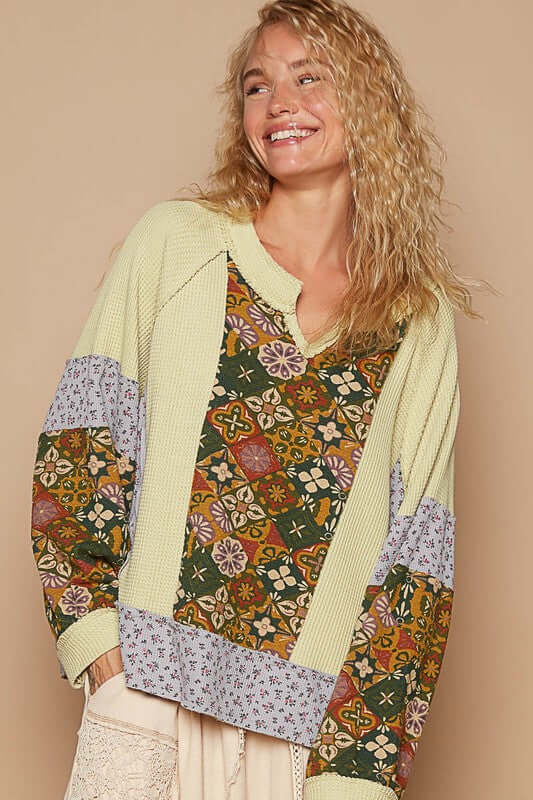 Trendy notched raglan sleeve knit top with vibrant patchwork patterns and cozy waffle-knit texture.