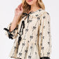 SAGE + FIG Bow Print Tie Front Babydoll Blouse in cream with black bow pattern and tie details, styled chicly.