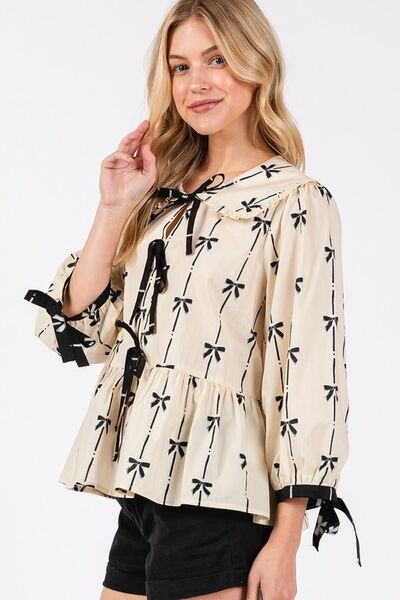 SAGE + FIG Bow Print Tie Front Babydoll Blouse in cream with black bow pattern and tie details, styled chicly.