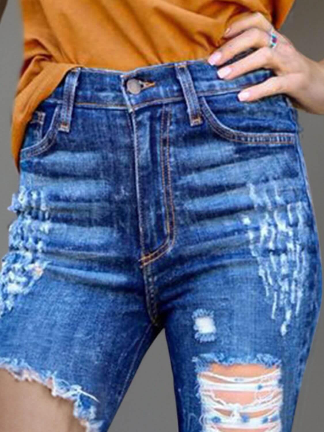 Woman wearing Raw Hem Distressed Bootcut Jeans with a trendy raw hem and stylish distressing detailing.