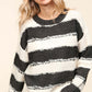 Woman wearing Haptics Striped Contrast Distressed Sweater in black and white, showcasing trendy and stylish design.