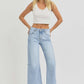 Woman wearing RISEN high rise seamed detail wide leg crop jeans with a white tank top and heels.