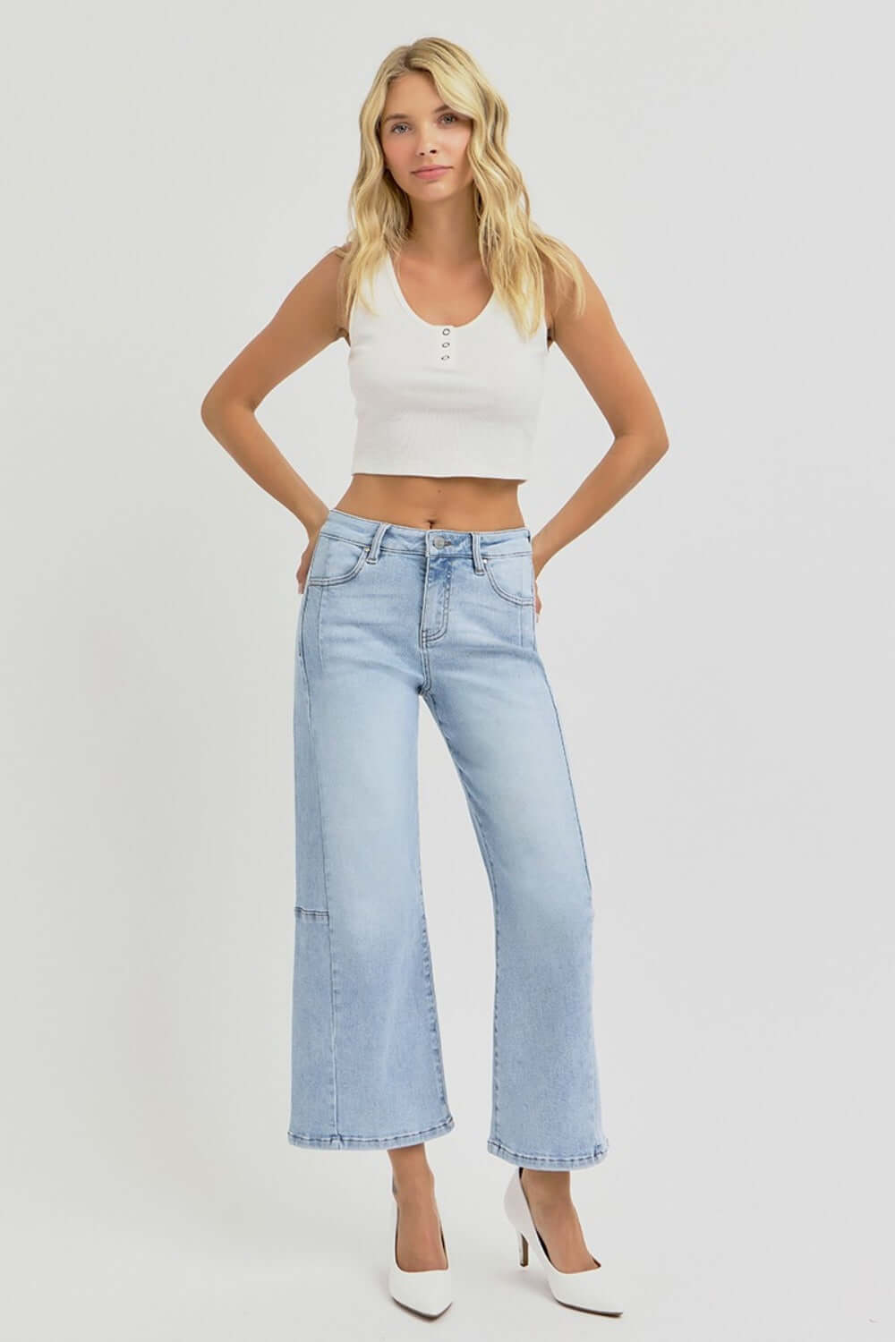 Woman wearing RISEN high rise seamed detail wide leg crop jeans with a white tank top and heels.