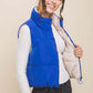 Trendy woman in a blue zip-up cropped reversible vest over a white top, showcasing style and versatility.