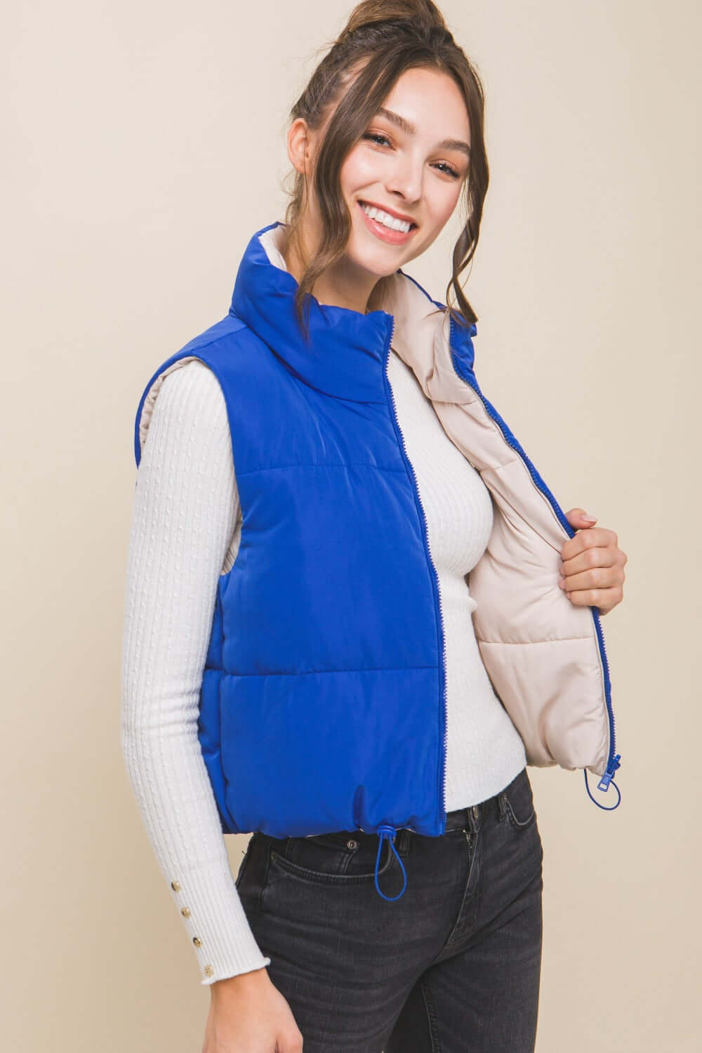 Trendy woman in a blue zip-up cropped reversible vest over a white top, showcasing style and versatility.