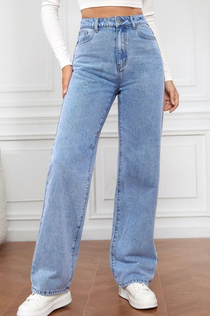 High Waist Straight Jeans in light blue denim with button closure and pockets, modeled with white sneakers in a stylish setting.