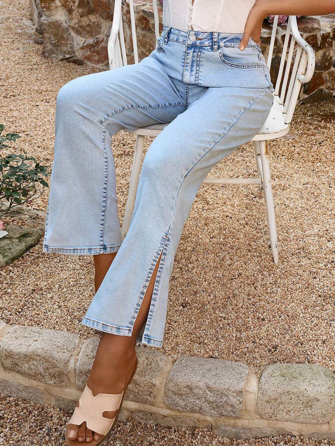 Light wash Bella Road side slit straight leg jeans with pockets, styled casually while sitting on a chair.