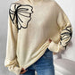 Woman wearing Perfee Mock Neck Dropped Shoulder Long Sleeve Sweater with black floral design, paired with blue jeans.