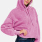 Woman wearing a Zenana Acid Wash Fleece Cropped Hoodie in pink, showcasing its trendy and edgy style with a cozy fleece fabric.