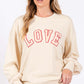 Woman wearing LOVE Path Applique Drop Shoulder Sweatshirt with round neckline and ribbed hems for a relaxed, stylish look.