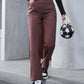 Stylish woman in dark brown denim straight leg jeans, holding a soccer ball handbag, ready for a casual outing.