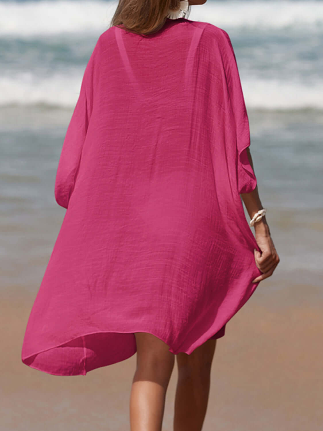 Woman wearing pink cutout V-neck three-quarter sleeve cover up on a beach