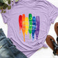 Lavender graphic round neck short sleeve t-shirt with 'Love Wins' rainbow paint design, paired with denim jeans and sandals.