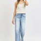 Woman wearing RISEN Full Size Tummy Control High Rise Crop Wide Leg Jeans in light wash with a white top and sandals