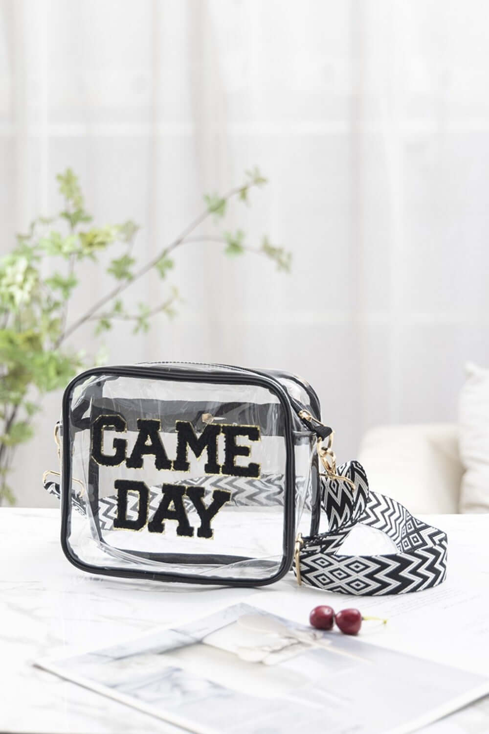 Transparent crossbody bag with "GAME DAY" letters, black glitter trim, and patterned strap, perfect for stadium security checks.