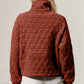 Woman wearing quilted half zip long sleeve sweatshirt with pocket in rust color, featuring stylish diamond pattern design.