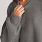 Woman wearing a cozy side slit round neck long sleeve sweater in a grey ribbed knit.