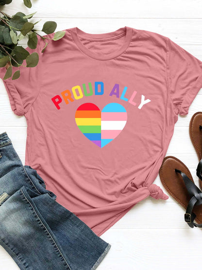 Pink round neck short sleeve t-shirt with "Proud Ally" text and rainbow heart design, displayed with jeans and sandals.