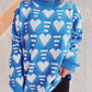 Woman wearing Bella Heart Contrast Long Sleeve Dropped Shoulder Sweater in blue with white hearts pattern.