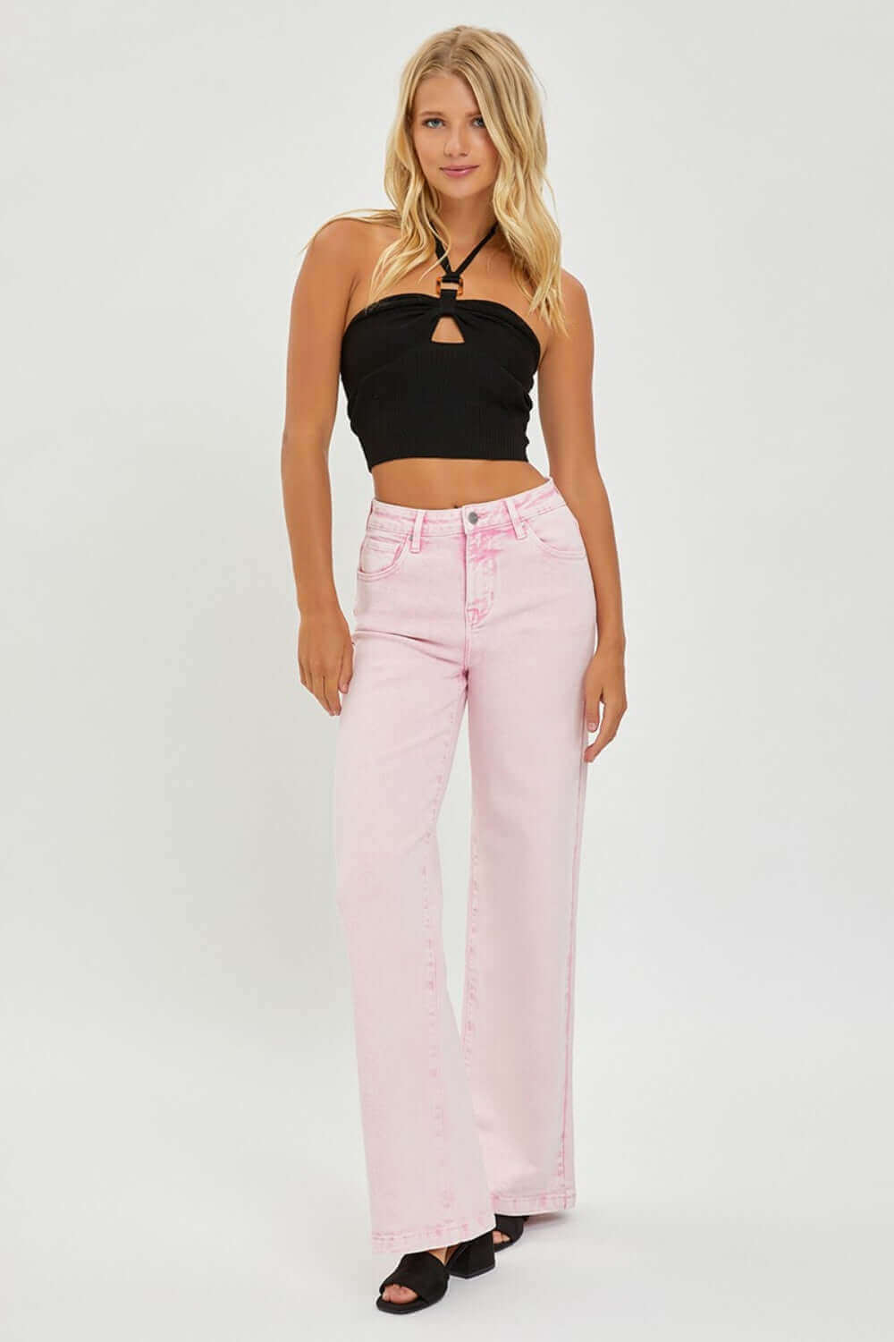 Stylish woman wearing high rise tummy control wide leg jeans in pink with a black crop top for a trendy look.