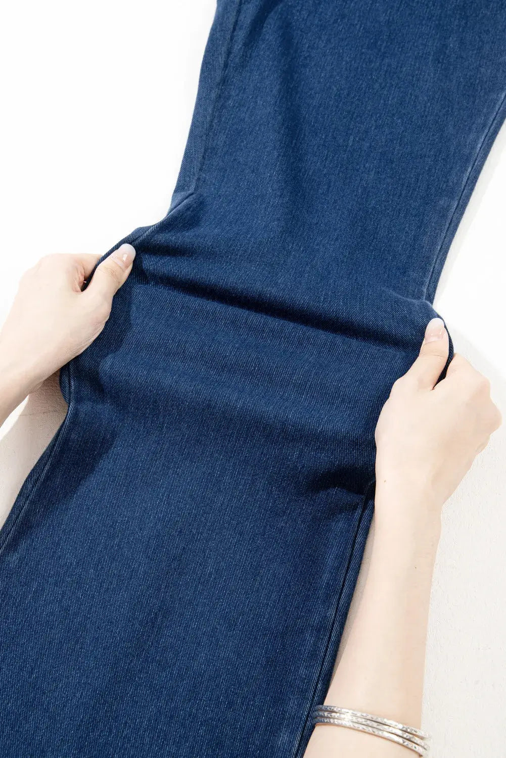 Demonstrating the stretch of blue straight jeans with pockets, showcasing the moderate stretchiness and comfortable material.