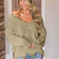 Woman wearing Bella Road frayed hem dropped shoulder sweater in cozy room, showcasing stylish and playful fashion.