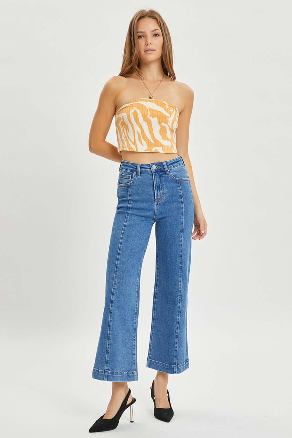 Model wearing high-rise wide-leg Risen Jeans for petite; styled with a strapless top and heels, showcasing a chic retro-inspired denim look