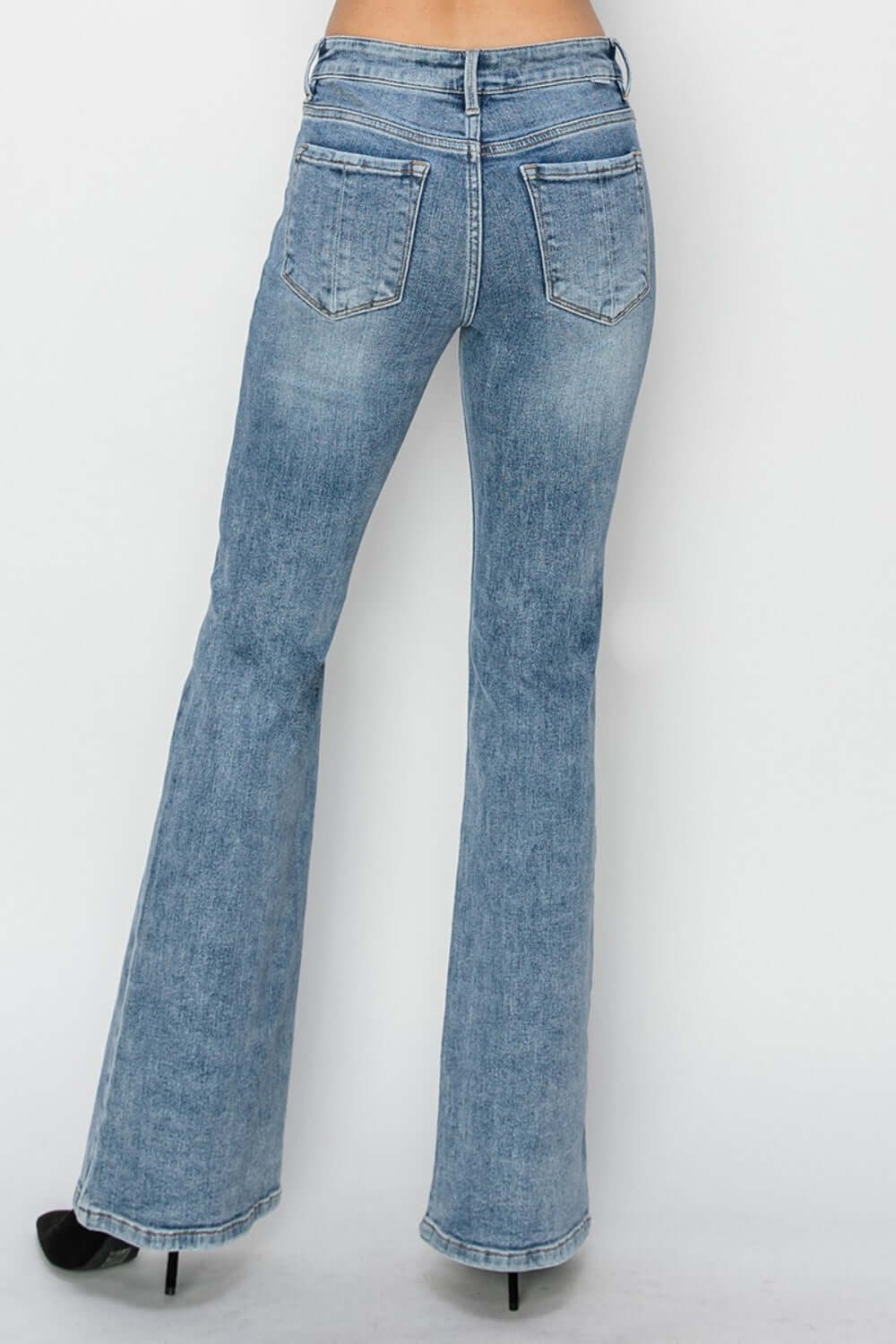 Back view of mid-rise bootcut Risen Jeans, showing a balanced silhouette and flattering style paired with black heels.