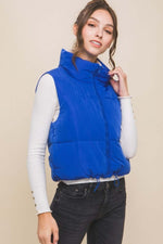 Stylish model wearing a blue zip-up cropped reversible vest over a white top, showcasing a modern layered look.