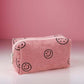 Cute pink corduroy cosmetic pouch with smiley face design, perfect for organizing makeup essentials on-the-go.