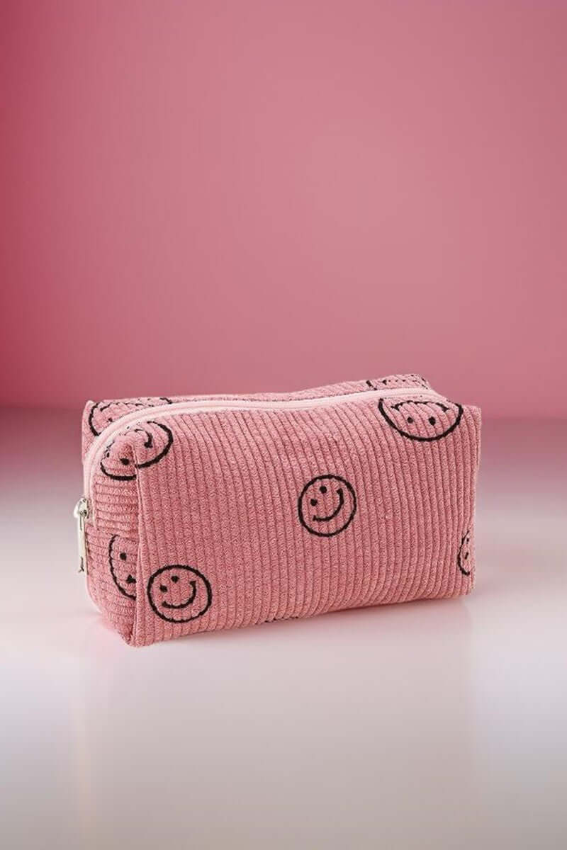 Cute pink corduroy cosmetic pouch with smiley face design, perfect for organizing makeup essentials on-the-go.