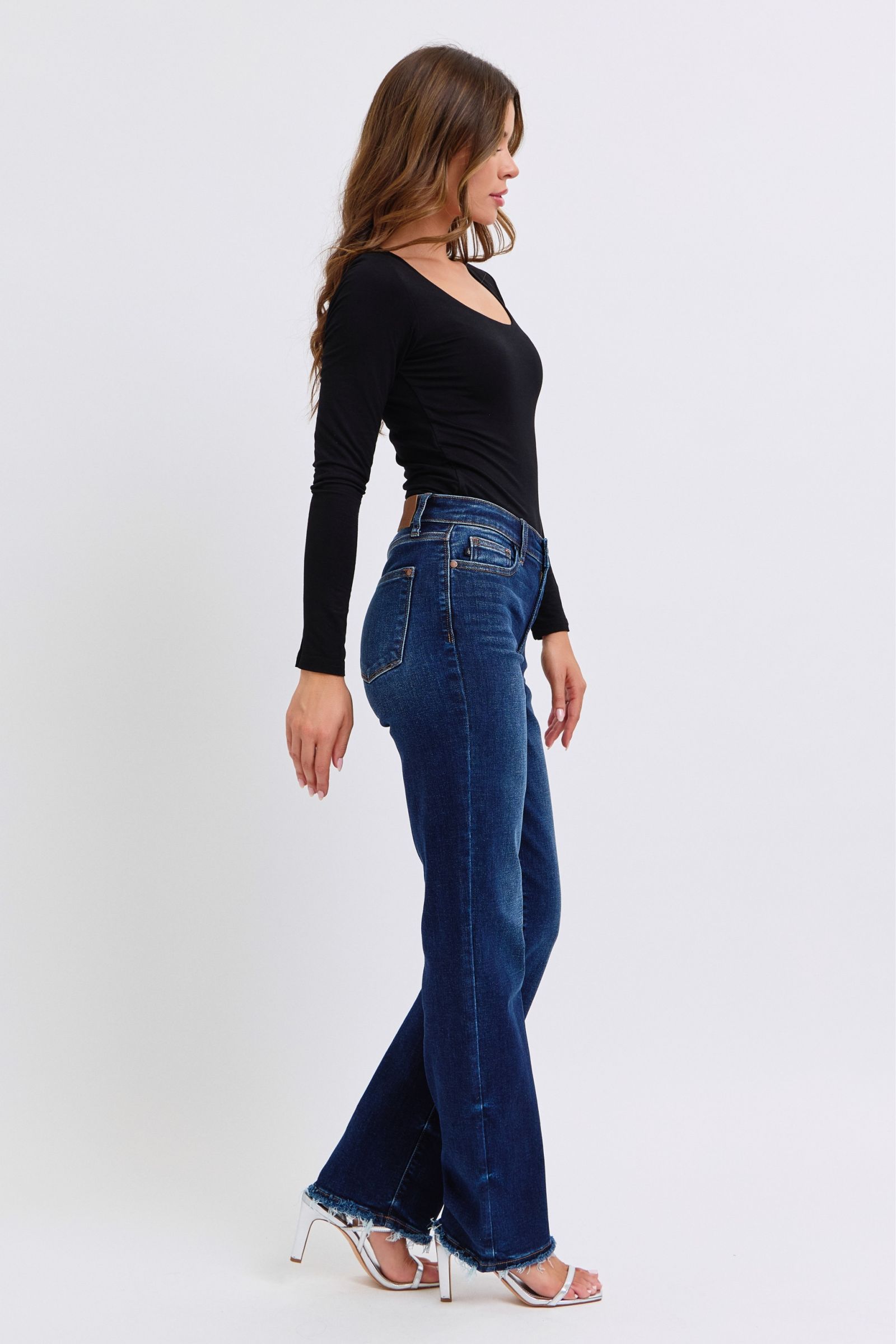 Stylish woman in Judy Blue raw hem straight leg jeans, side view showcasing timeless style and flattering fit.