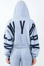 Back view of American Bazi 'New York' cropped hoodie showcasing bold graphic design and drawstring detail.