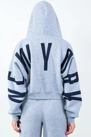 Back view of American Bazi 'New York' cropped hoodie showcasing bold graphic design and drawstring detail.