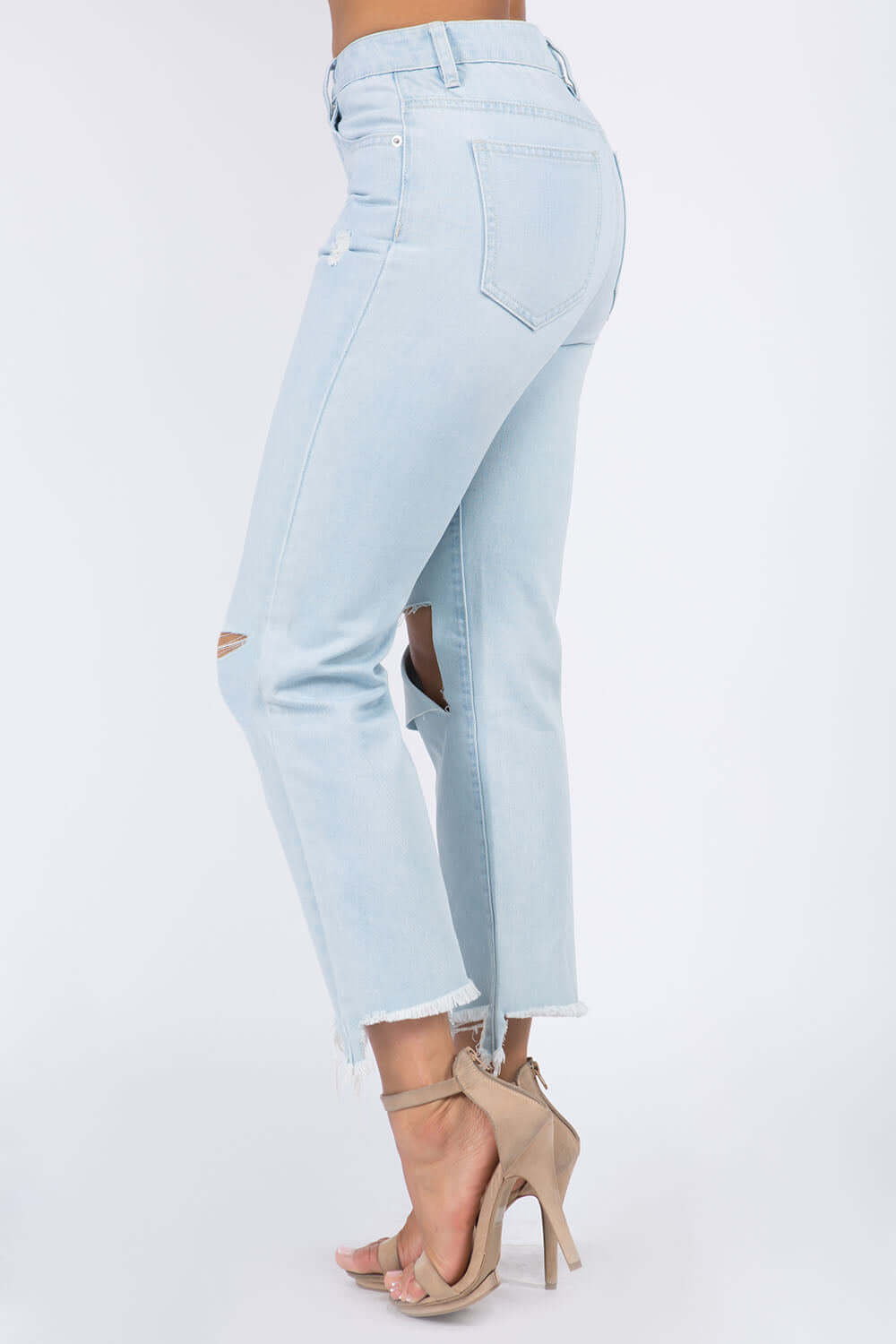 High Waist Distressed Raw Hem Jeans in light wash, featuring a flattering fit and trendy distressed details, worn with beige high heels.