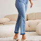 Woman wearing Judy Blue release hem cropped bootcut jeans paired with white heels in a stylish living room setting.