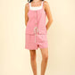 Woman wearing a chic pink half-button drawstring sleeveless romper perfect for casual day out or fun night with friends.