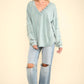 Woman wearing VERY J Washed V-Neck Exposed Seam Knit Top with long sleeves, drop shoulder design, and distressed jeans.