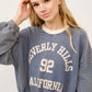 Woman in BEVERLY HILLS 92 CALIFORNIA cropped sweatshirt with contrast detailing