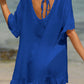 Woman wearing a blue tied ruffled half sleeve cover-up on the beach, back view showing sheer, non-stretch material.