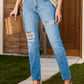 Woman wearing distressed buttoned jeans with pockets, holding a wicker bag and wearing nude heels.