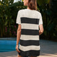 Woman wearing the Bella Road Swim Openwork Cover-Up with black and white stripes by the pool surrounded by tropical greenery.