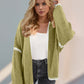 Trendy woman wearing green Double Take Contrast Cardigan with open front and dropped shoulders for a chic, relaxed look.