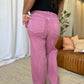 Woman wearing RFM High Rise Garment Dye Wide Leg Jeans in rich pink color, showing back view and relaxed fit in a chic setting.