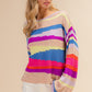 Woman wearing a BiBi Multi Color Geometric Stripe Sweater, showcasing vibrant modern stripes in a cozy knit fabric.