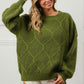 Model wearing a green BiBi diamond texture round neck long sleeve sweater styled with white shorts, showcasing casual elegance.