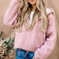 Woman wearing pink Sherpa drawstring cropped hooded jacket with casual jeans against a beige background.