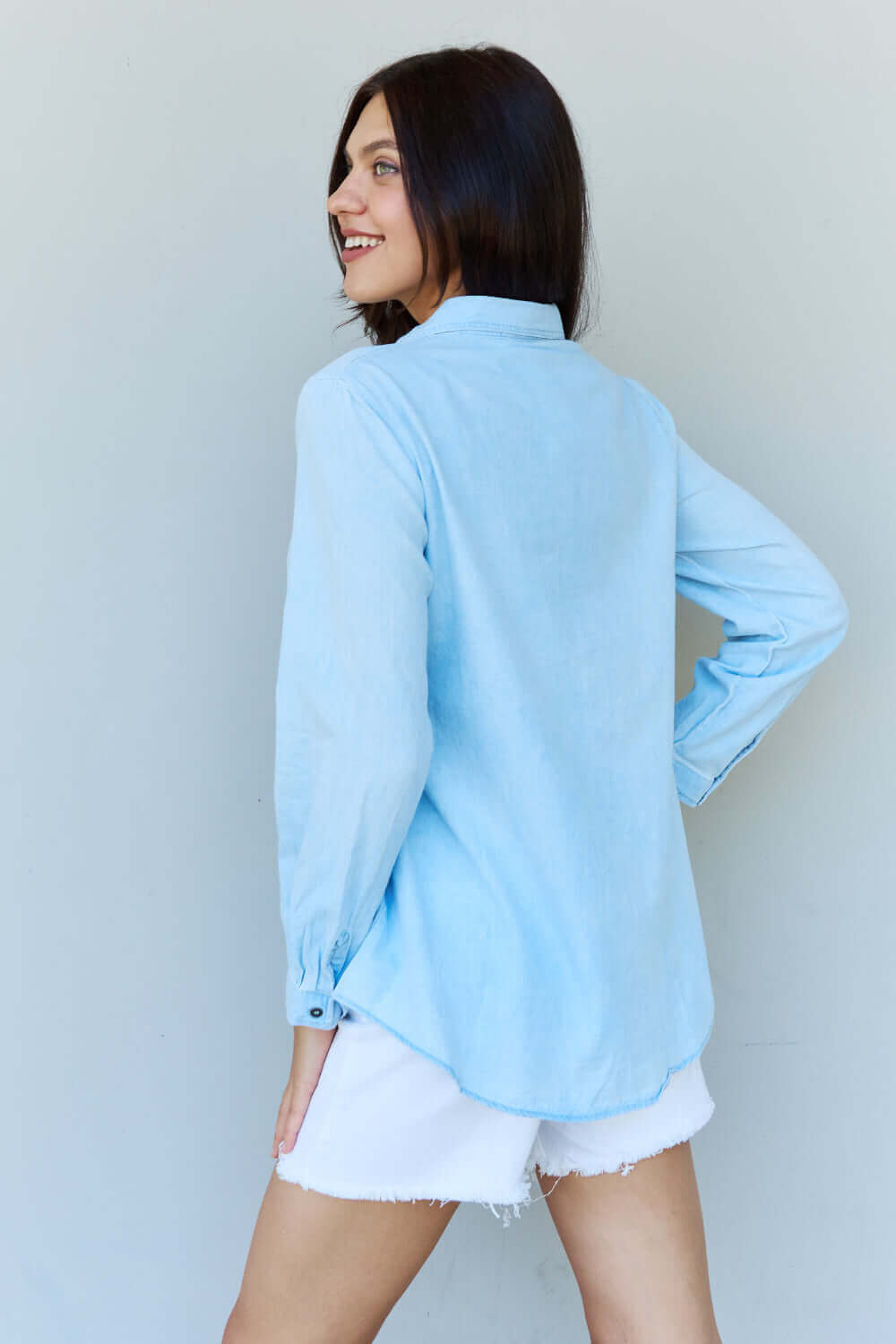 Woman wearing Blue Jean Baby Denim Button Down Shirt in Light Blue, showing back view with long sleeves and buttoned cuffs.