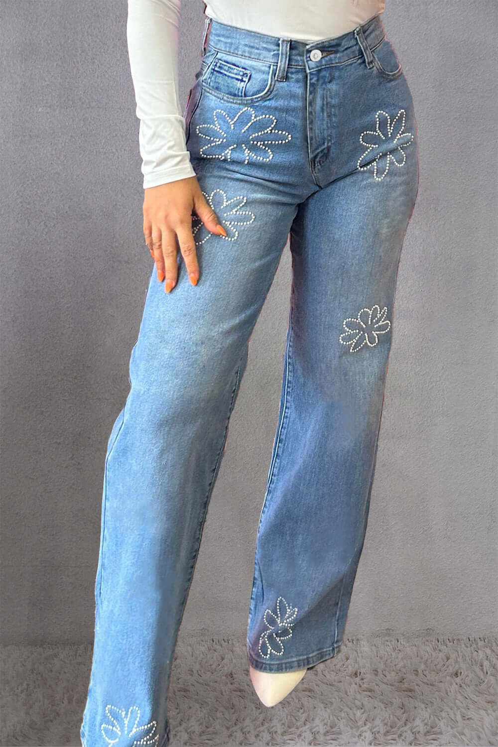 Woman wearing blue rhinestone straight jeans with floral designs and pockets. 75% cotton, 23% polyester, 2% elastane. Machine wash cold.